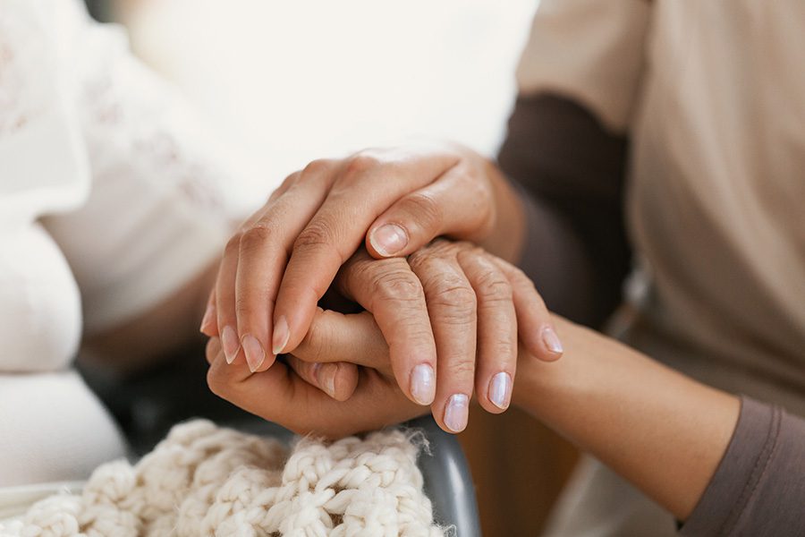 Final Expense Insurance - Closeup of a Woman Holding Hands with a Senior Patient