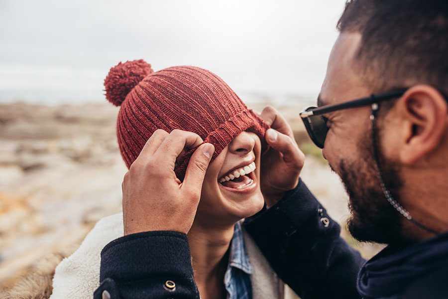 Contact - Portrait of a Joyful Young Couple Having Fun Playing Together Outside by the Coast During the Winter