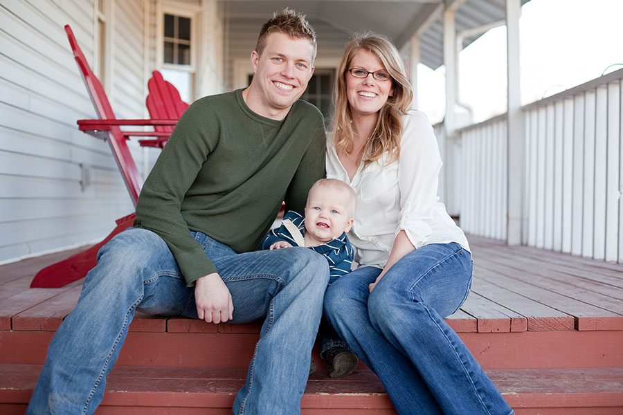 Personal Insurance - Portrait of a Cheerful Family with a Young Toddler Sitting on the Front Porch Steps of Their Country Home
